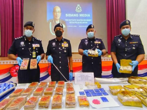 Shafien (dua dari kiri) menunjukkan dadah jenis heroin base seberat 13.295kg dan 86,000 biji pil yaba bernilai RM2.09 juta selepas menahan seorang pemandu lori di jalan Pasir Mas-Tanah Merah, Pasir Mas pada Ahad.