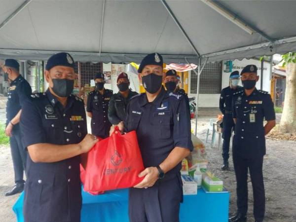 Mior Faridalathrash (depan, kanan) menyerahkan bakul makanan kepada Ketua Polis Daerah Tapah, Superintendan Wan Azharuddin Wan Ismail di PKTK Batu 7, Jalan Pahang, Tapah pada Khamis.