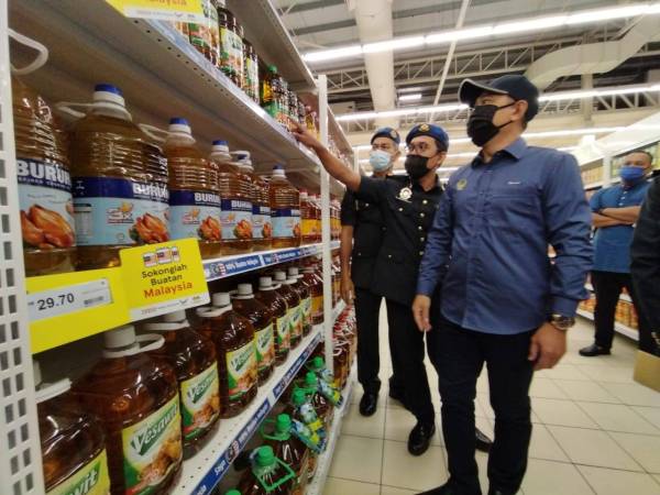 Abdul Yunus (kanan) bersama KPDNHEP Perak menjalankan pemeriksaan dan pemantauan harga minyak sawit botol di sebuah pasar raya di Taiping pada Jumaat.