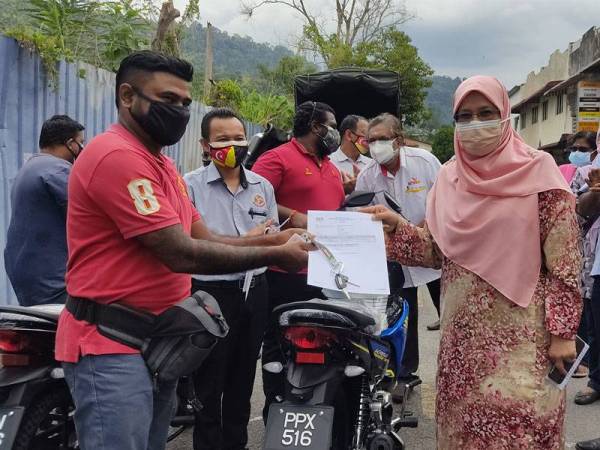 Rodziah (tiga dari kanan) menyerahkan geran motosikal kepada Sivaneshwaran di hadapan Pusat Sehenti Sitham di Ampang Jaya pada Sabtu.