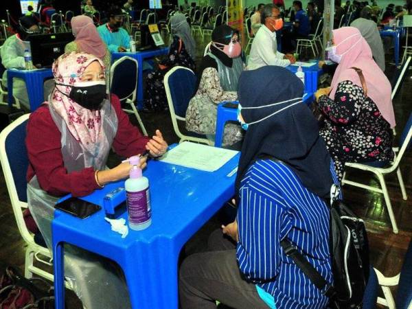 Suasana ketika petugas menyantuni penerima yang hadir mendapatkan suntikan vaksin dos pertama di Dewan Mu’adzam Shah, UUM. Foto UUM