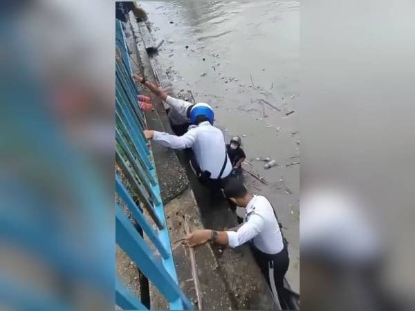 Dua orang anggota JSPTKL berusaha menyelamatkan tiga beranak yang hampir hanyut di Sungai Klang pada Ahad. Foto: Facebook Ahyie Hairi