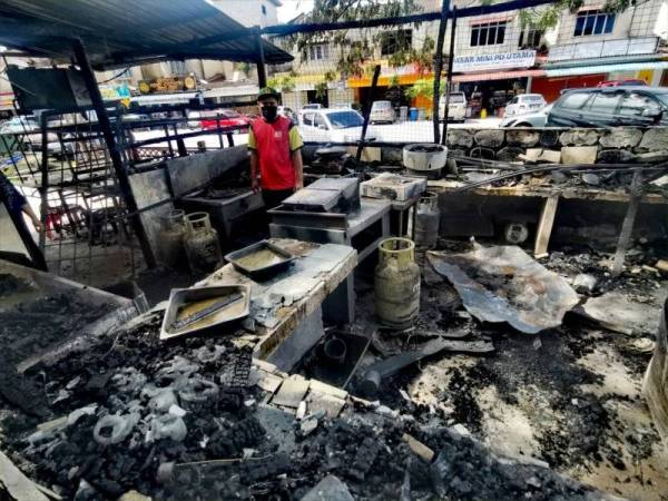 Mohd Johaimay melihat keadaan kedainya yang musnah terbakar di Taman PD Utama, Port Dickson pada Selasa.