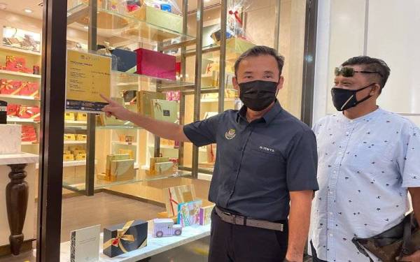 Tung Seng menunjukkan poster maklumat vaksinasi yang perlu dipaparkan pada pintu masuk premis di Medan Selera Gurney Paragon, Georgetown pada Khamis.