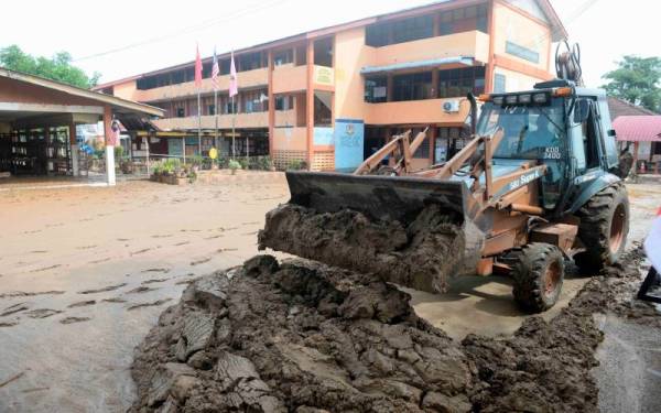 Kerja-kerja pembersihan menggunakan jentolak di pekarangan sekolah sedang giat dilakukan untuk membuang lumpur di Sekolah Kebangsaan Haji Nyak Gam hari ini. Foto Bernama