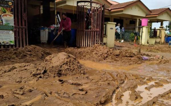 Seorang penduduk sedang membersihkan rumah di Taman Lembah Merbok yang dilanda banjir lumpur akibat fenomena kepala air.