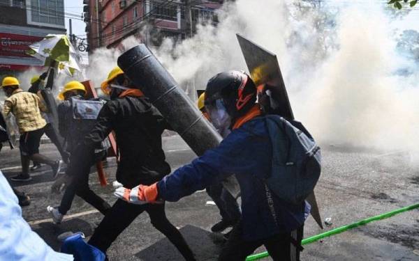 Gambar fail menunjukkan para penentang rampasan kuasa tentera cuba melindungi diri daripada terkena gas pemedih mata pihak berkuasa di Yangon, Myanmar. - Foto AFP