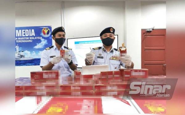 Muhammad Suffi (kanan) menunjukkan sebahagian rokok seludup yang dirampas dari kawasan pantai Pulau Karah, berhampiran Pulau Bidong, di Kuala Nerus, pada Sabtu.