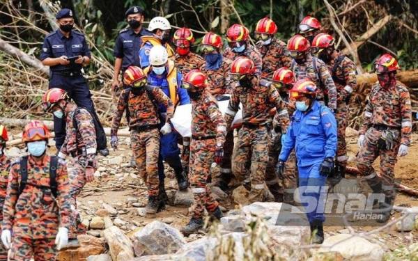 Anggota SAR mengeluarkan mangsa yang ditemukan di bawah timbunan kayu di kawasan air terjun Titi Hayun, Yan pada Isnin.