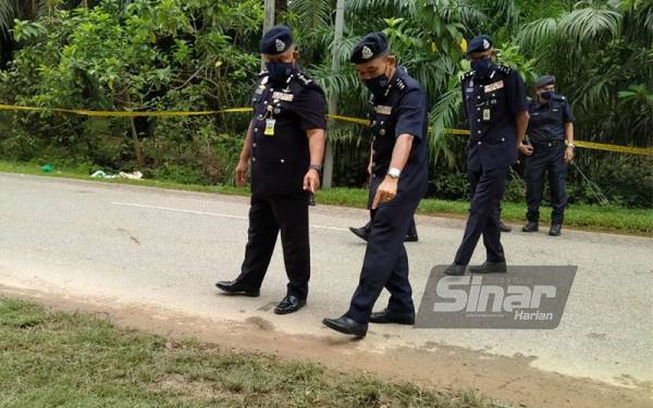 Kamarul Zaman (kiri) memeriksa lokasi kejadian pembunuhan dekat jalan utama Kongsi 14 pada Selasa.