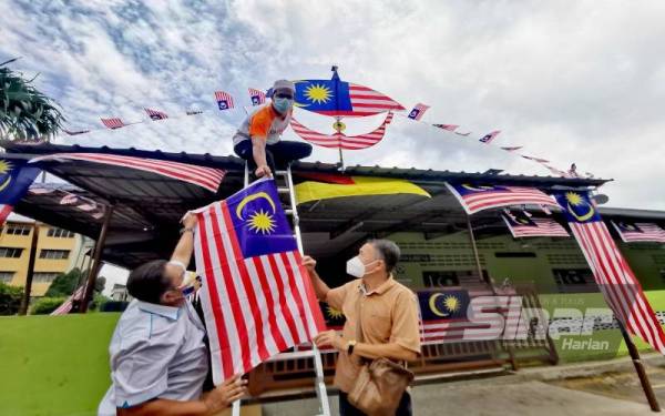 Md Fakarudin (kiri) memberi Jalur Gemilang kepada Romli Wahab, 51, untuk dipasang di atas bumbung masjid.