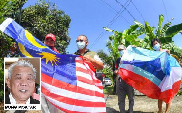 Pengerusi Jawatankuasa Pembangunan dan Keselamatan Kampung Sagap, Siwin (kiri) dan Ketua Kampung Tombovo, Simon Susiang (dua, kanan) membantu Johnny Abol dan Martha Abol memasang Jalur Gemilang dan Bendera Negeri Sabah di halaman rumah mereka di Kampung Tombovo. - Foto Bernama