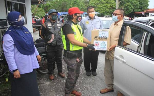 Mohd. Razmi (tiga dari kiri) menyerahkan sumbangan barangan makanan kepada pemandu teksi dan limosin di LTAPP di Bayan Lepas hari ini.