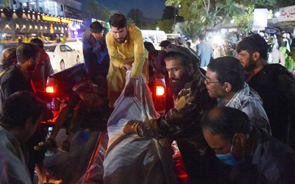 Sukarelawan dan petugas kesihatan membawa keluar mayat ke dalam sebuah kenderaan pikap di luar hospital di Kabul. - Foto AFP