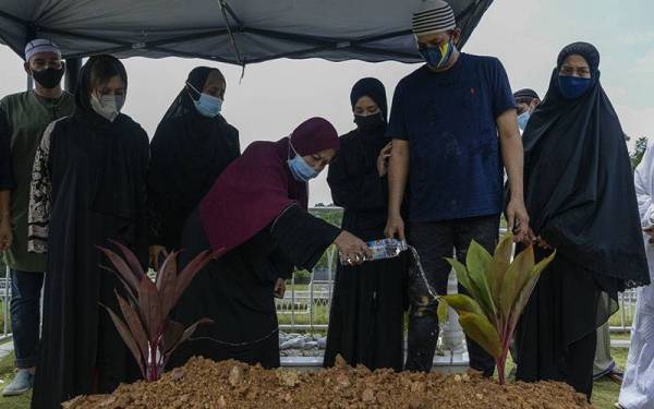 Balu kepada Tun Ahmad Sarji Abdul Hamid, Toh Puan Sagiyah Salikin (empat, kiri) menyiram air ke pusara suaminya yang merupakan bekas Ketua Setiausaha Negara (KSN) di Tanah Perkuburan Islam Raudhatul Sakinah II, Bukit Kiara hari ini. - Foto Bernama