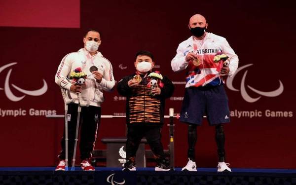 Atlet powerlifting paralimpik negara, Bonnie Bunyau Gustin (tengah) bergambar dengan atlet dari Mesir dan Great Britain, Attia Mahmoud (kiri) dan Yule Micky setelah berjaya meraih pingat emas pertama negara bagi kategori 72 kilogram (kg) pada Kejohanan Sukan Paralimpik Tokyo 2020 di Tokyo International Forum hari ini. Foto Bernama