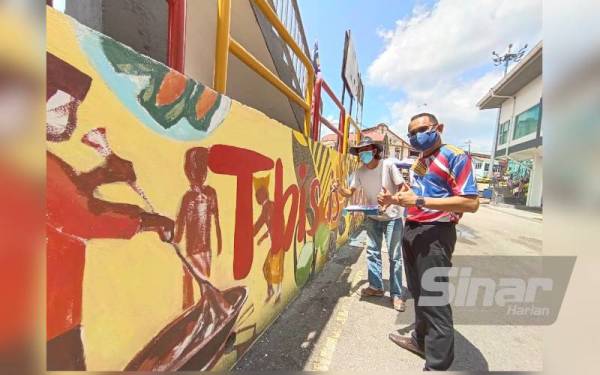 Mohd Faizal (kanan) bersama Zorro ketika meninjau mural berkenaan di Hentian Kuala Pilah pada Sabtu.