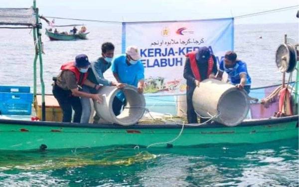 Azman (dua dari kanan) membantu melabuhkan unjam di Marang pada Ahad.