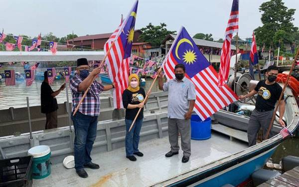 Azli ( dua dari kanan) dan Intan Suhaila ( dua dari kiri) pada gimik pelepasan 30 bot nelayan yang dihiasi Jalur Gemilang berarak di Sungai Masai Besar pada Isnin.