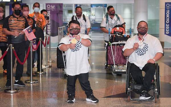 Reaksi atlet powerlifting paralimpik negara Bonnie Bunyau Gustin (tengah) ketika tiba di Lapangan Antarabangsa Kuala Lumpur (KLIA) hari ini. -Foto Bernama