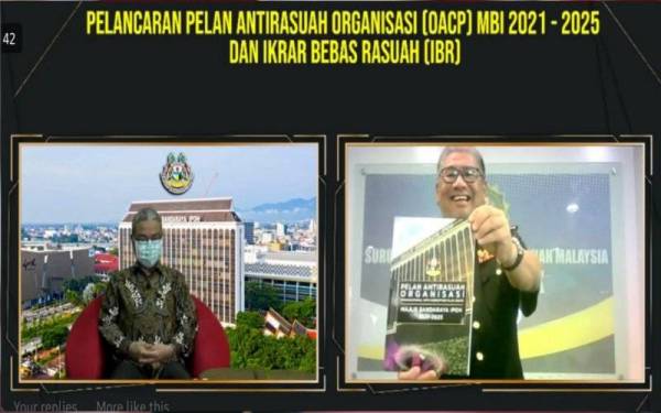 Mohd Fauzi (kanan) menerima buku OACP MBI 2021-2025 daripada Rumaizi (kiri) simbolik pelancaran OACP berkenaan dan Ikrar Bebas Rasuah (IBR) yang diadakan secara maya di Ipoh pada Khamis.