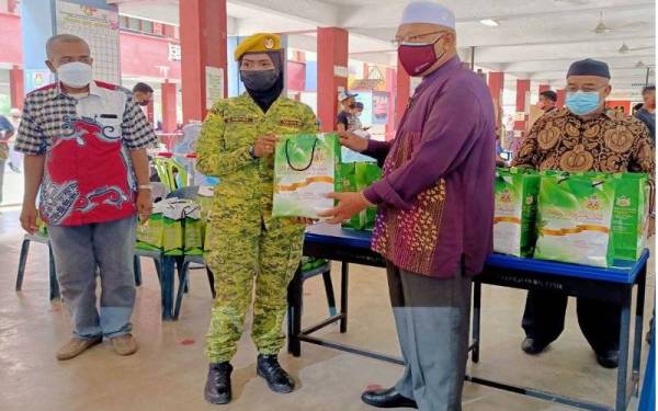 Ahmad (kanan) menyampaikan cenderamata kepada petugas barisan hadapan semasa mengadakan lawatan ke Program Outreach Vaksinasi Peringkat Dewan Undangan Negeri (DUN) Pasir Pekan di Sekolah Kebangsaan (SK) Kampung Laut, Tumpat pada Khamis