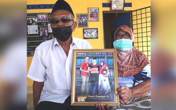 Siti Rubiah dan suaminya menunjukkan gambar kenangan Nazli yang terbabit dalam kemalangan di Kilometer 43.5 Lebuhraya Kuala Lumpur-Karak pada Khamis.