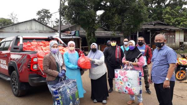 Zulaikha (dua dari kiri) menyerahkan sumbangan makanan kepada Badariah di pekarangan rumahnya di Kampung Masjid, Masai, Pasir Gudang pada Jumaat.