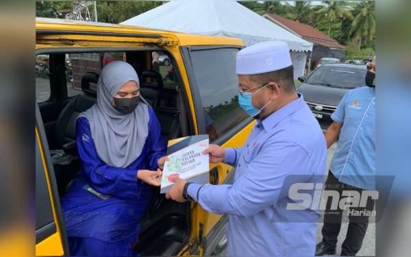 Marzuk (kanan) menyampaikan Anugerah Kecemerlangan secara pandu lalu di Pejabat Pusat Khidmat Ahli Dewan Rakyat di Pengkalan Chepa pada Sabtu.