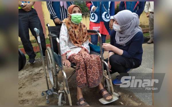 Rina menyantuni mangsa tragedi, Kalsom Md Aris, 84, ketika memantau lokasi bencana sekitar Jalan Masjid Yan pada Sabtu.