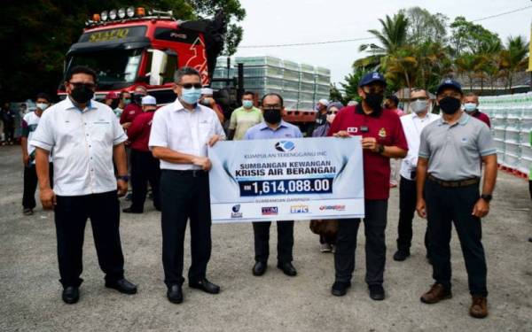 Ahmad Samsuri (depan, tengah) turun padang bagi mengagihkan air minuman kepada penduduk terjejas krisis air di Dewan Sivik Buluh Gading di Kuala Nerus pada Sabtu.