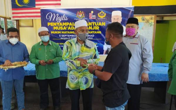 Idris (tengah) sampaikan sumbangan kepada seorang mangsa banjir ketika hadir menyampaikan Bantuan Musa'adah Banjir di Dewan Orang Ramai Matang Gelugor, Matang, Taiping pada Ahad.