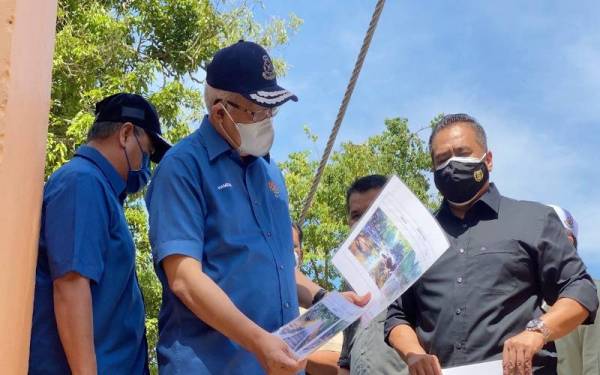 Hamzah melihat gambar kawasan Peranginan Titi Hayun sebelum dilanda bencana kepala air pada 18 Ogos lalu ketika membuat tinjauan di sekitar kawasan peranginan terbabit dalam Program KDN Prihatin di sini pada Ahad.