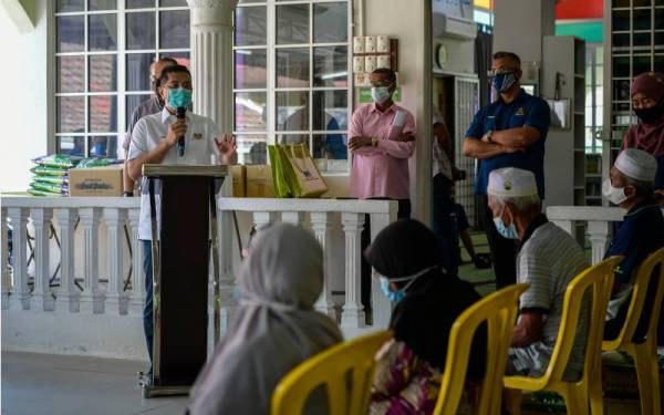 Azmin (kiri) menyampaikan ucapan pada majlis penyampaian sumbangan bantuan dan Program Penyerahan Foodbank di Surau Al-Iman, Kampung Melayu Sri Gombak, hari ini. - Foto Bernama