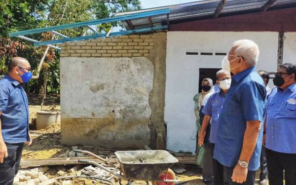 Mahdzir (kanan) melihat rumah seorang penduduk, Fatimah Ali, 83, yang dibaiki oleh KEDA di Kampung Setol di sini pada Isnin.