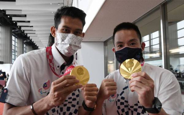 Abdul Latif (kiri) bersama atlet badminton para negara, Cheah Liek Hou menunjukkan pingat emas yang dimenangi mereka pada Sukan Paralimpik Tokyo 2020 sebelum berlepas pulang di Lapangan Terbang Antarabangsa Narita pada Isnin. - Foto Bernama