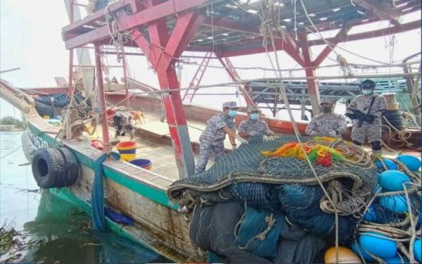 Syed Nor Adli (kiri) menunjukkan salah satu bot nelayan Vietnam yang ditahan oleh Kapal Maritim (KM) Tok Bali pada Khamis.