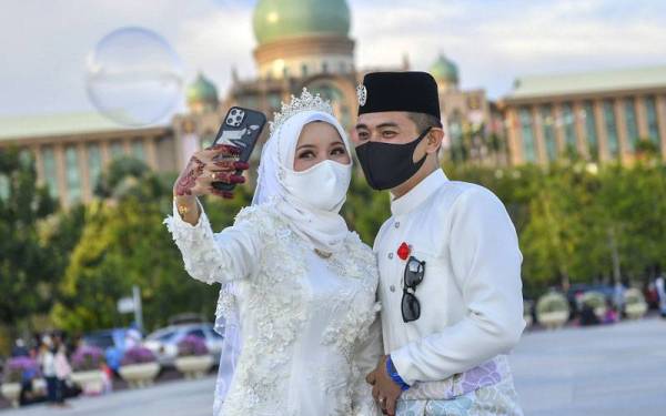 June Asmerahawa berswafoto dengan pasangannya, Mohd Fauzi berlatar belakangkan Bangunan Perdana Putra di Dataran Putra, Putrajaya selepas majlis akad nikah di Jawi Kuala Lumpur pada Jumaat. - Foto Bernama