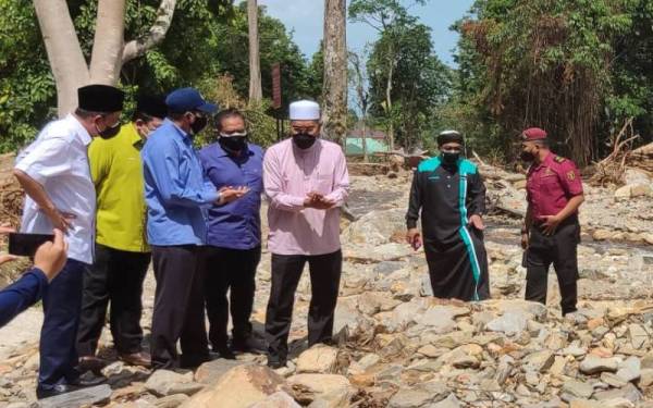 Idris (lima dari kiri) mendengar penerangan berhubung kesan kejadian banjir kepala air semasa melawat Pusat Rekreasi Titi Hayun, Yan pada Sabtu.