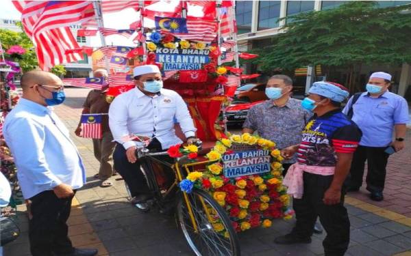 Ahmad Marzuk cuba mengayuh beca pada program musaadah Yayasan dakwah Islamiah Malaysia (Yadim)-Bank Islam kepada pengayuh beca di Dataran Muhammadi, Kota Bharu pada Sabtu.