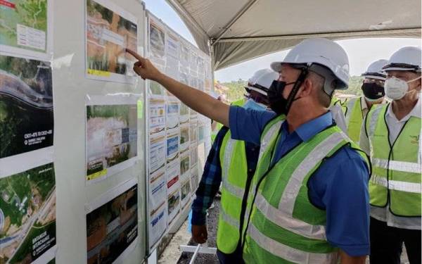 Fadillah melihat gambar pembinaan jambatan Sungai Sarike ketika meninjau tapak WPC 06 Lebuh Raya Pan Borneo di Bintangor pada Sabtu. - Foto Bernama