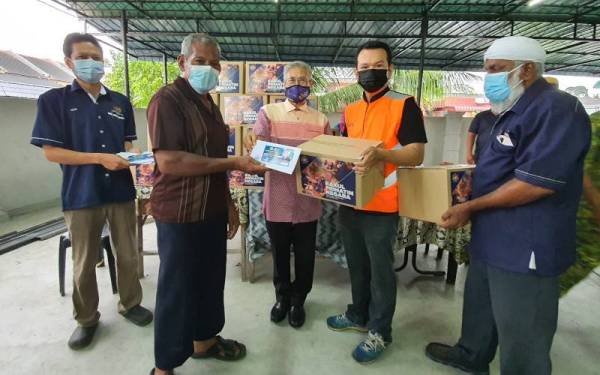 Mansor (tengah) menyampaikan bantuan kepada salah seorang mangsa ribut di Kampung Tasek Cempedak.