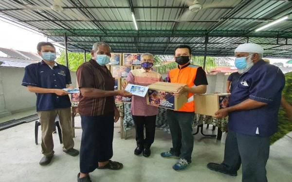 Mansor (tengah) menyampaikan bantuan kepada salah seorang mangsa ribut di Kampung Tasek Cempedak.