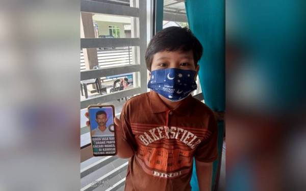 Anak bongsu Kasiah, Wan Muhammad Syakir Wan Abd Manan, 8 menunjukkan gambar ayahnya yang hilang semasa dia baharu berusia 4 tahun