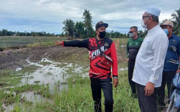 Razman (kanan) mendengar masalah daripada pesawah, Shaiful Shahrin Ahmad Fuzi berikutan keadaan petak sawah yang kurang air untuk mulakan tanaman padi.