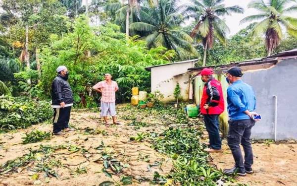 Mohd Zakhwan ( kiri) bersama Saari (dua,kiri) melihat keadaan belakang rumah.