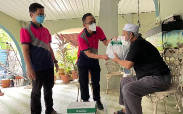 Mohamad Kairi (tengah) menyerahkan bantuan kepada Mohamad ketika mengunjungi di rumahnya di Seberang Jaya.