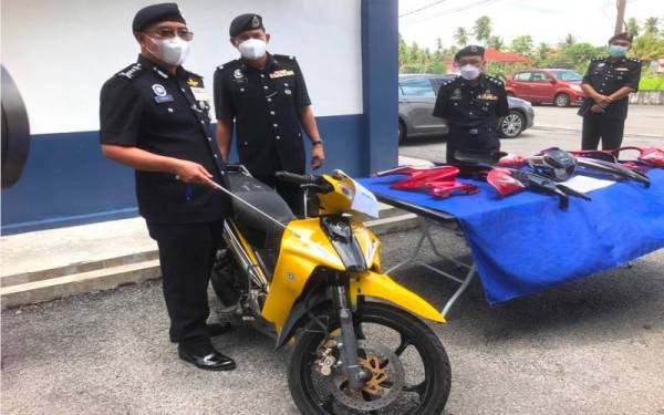 Shafien (kiri) menunjukkan motosikal suspek yang dipercayai digunakan dalam kejadian membakar Pondok Polis Pasar Jelawat, Bachok pada Sabtu lalu.