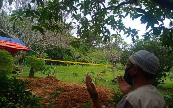 Wan Mohd Assamudin mendoakan bapanya di pekarangan Tanah Perkuburan Islam Kampung Padang Gelanggang, di sini, pada Rabu.