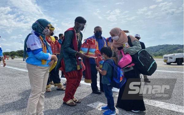 Nancy (kiri) bersama Menteri Besar Kedah, Muhammad Sanusi Md Nor (tiga,kiri) menyambut kedatangan pelancong yang tiba di Langkawi pada hari pertama Projek Rintis Gelembung Pelancongan Langkawi di sini pada Khamis.